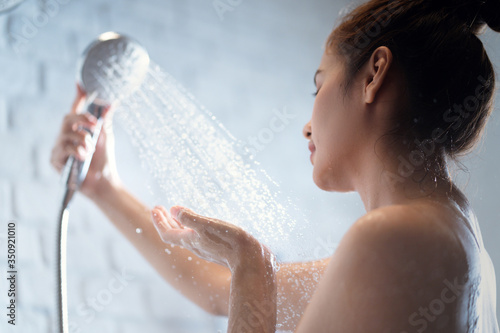 Obraz na plátně Asian woman takes a shower and uses her hands to touch the water.