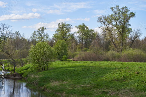 A winding river with steep banks, grass and trees