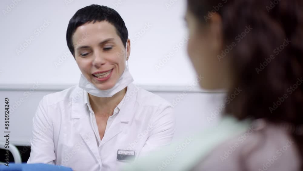 Sequence of cheerful female dentist in white coat consulting female patient sitting on dental chair. She is showing her x-ray on tablet and suggesting treatment Sequence of cheerful female dentist in white coat consulting female patient sitting on dental chair. She is showing her x-ray on tablet and suggesting treatment