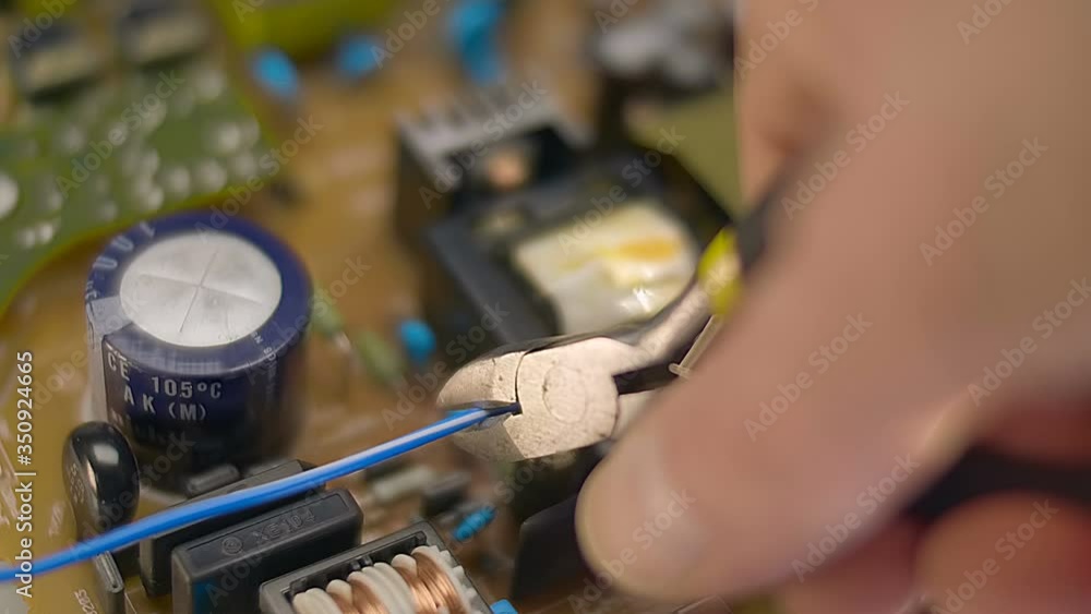 Nippers in hand cut the blue (red) wire on the background of the electric board. Macro. Closeup. Shallow depth of field
Nippers in hand cut the blue (red) wire on the background of the electric board. Macro. Closeup. Shallow depth of field