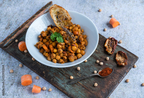 Bowl of chickpeas surrounded by its main ingredients on a wooden board