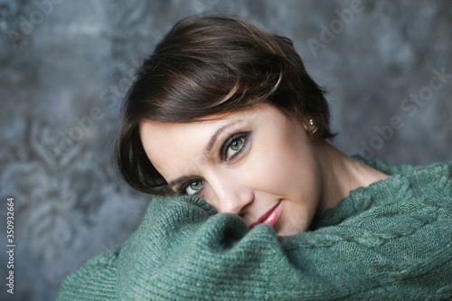 Portrait of a young brunette with green eyes in a green sweater with smoky makeup