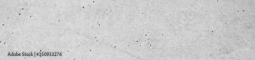 Concrete wall with holey structure in widescreen format. Horizontal cement wall with slightly rough plastering.