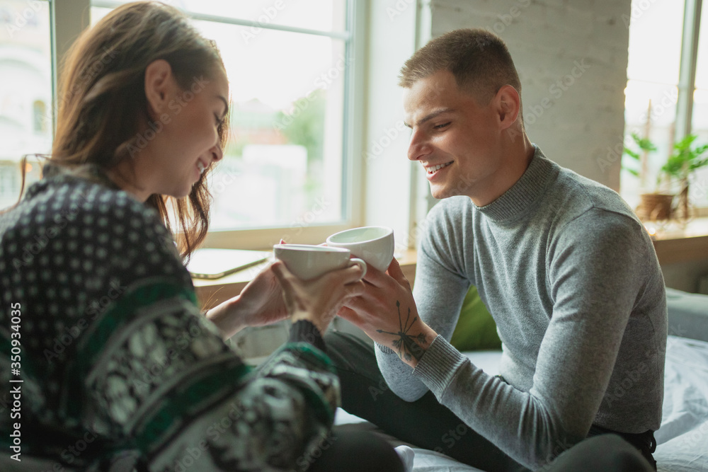 Drink tea, calm. Quarantine lockdown, stay home concept - young beautiful caucasian couple enjoying new lifestyle during coronavirus worldwide health emergency. Happiness, togetherness, healthcare. Drink tea, calm. Quarantine lockdown, stay home concept - young beautiful caucasian couple enjoying new lifestyle during coronavirus worldwide health emergency. Happiness, togetherness, healthcare.