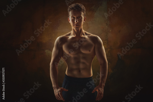  Athletic man posing. Photo of man with perfect physique on grunge background. Strength and motivation.