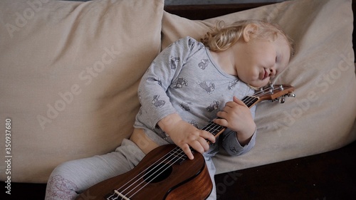 little girl plays the ukulele and goes to sleep look at the camera