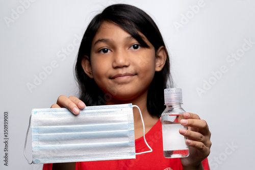 Asian girl on white background showing a face mask and hand sanitizer to protect and prevent the spread of the virus. Coronavirus disease 2019 (COVID-19) outbreak. photo