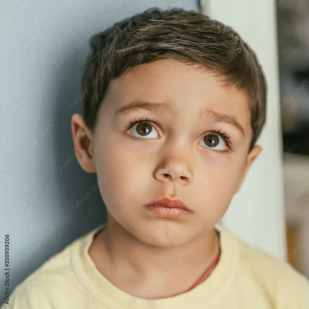 portrait of pensive, adorable brunette boy looking up with brown eyes portrait of pensive, adorable brunette boy looking up with brown eyes