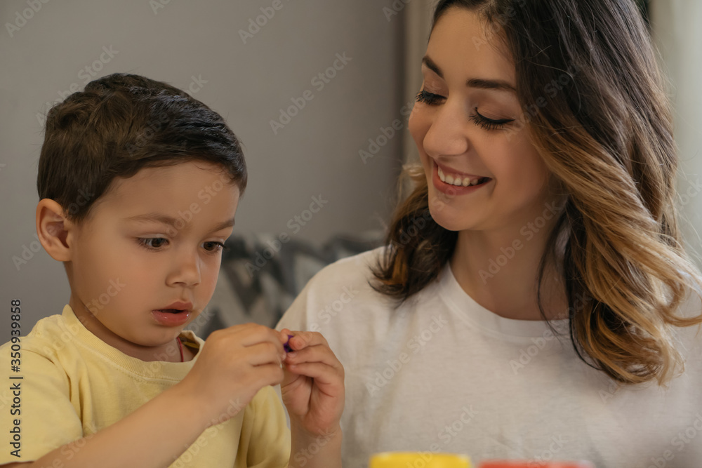 cheerful woman looking at son sculpting plasticine figure cheerful woman looking at son sculpting plasticine figure