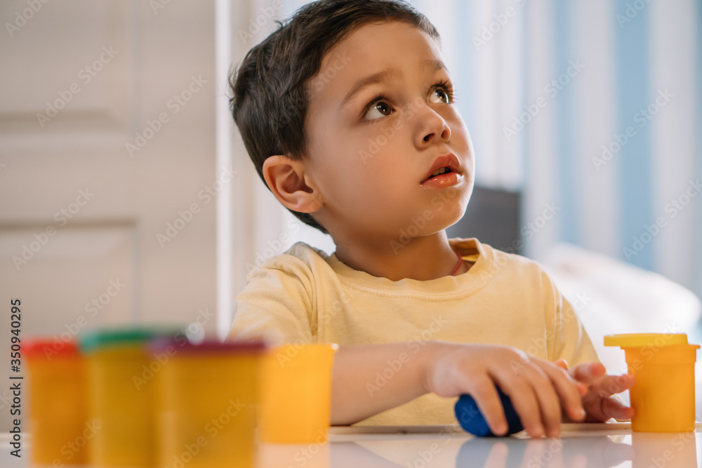 selective focus of thoughtful boy looking up while holding colorful plasticine selective focus of thoughtful boy looking up while holding colorful plasticine