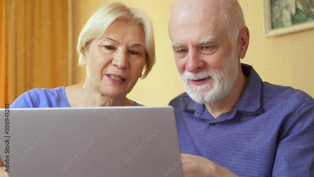Senior couple at home using laptop. Retired family working on computer learning social media. Computer literacy among elderly people, active modern lifestyle on retirement Senior couple at home using laptop. Retired family working on computer learning social media. Computer literacy among elderly people, active modern lifestyle on retirement
