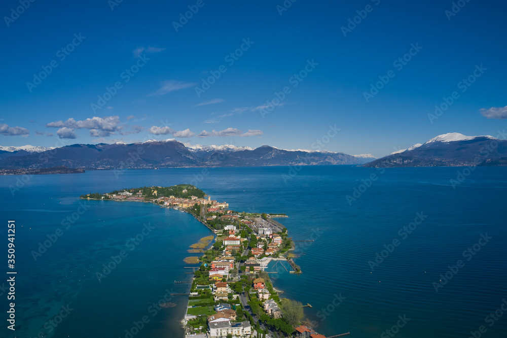 Sirmione town, Lake Garda, Italy. Aerial view of Sirmione.   In the background mountains in the snow and blue sky
