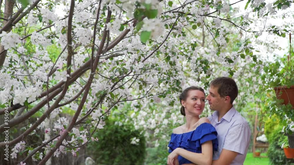 Tender Young Couple Embracing in a Spring Blooming Apple Garden. Concept of Spring, Love, Togetherness and Romantic Relationships Tender Young Couple Embracing in a Spring Blooming Apple Garden. Concept of Spring, Love, Togetherness and Romantic Relationships