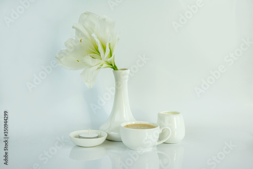 Coffee, milk, a flower, a candle are in a white bowl on a white background.