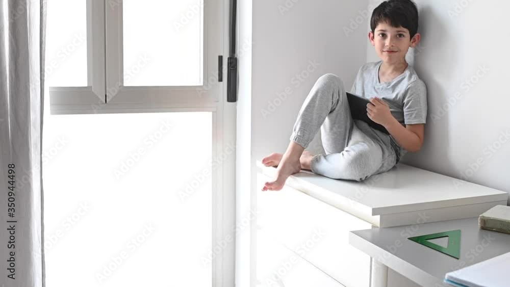 A boy playing tablet after doing homework. Home shooler. Social distance during quarantine. A boy playing tablet after doing homework. Home shooler. Social distance during quarantine.