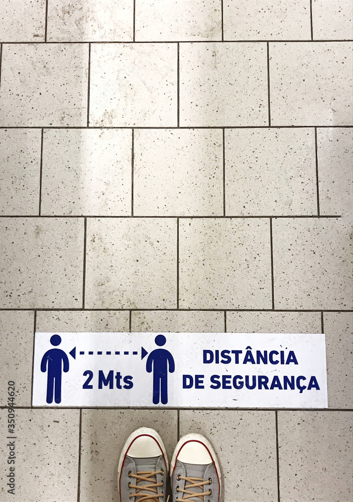 Person standing on tiled floor against a red line with the words 'keep your distance'. Concept of keep distance, social distancing. Film grain. Person standing on tiled floor against a red line with the words 'keep your distance'. Concept of keep distance, social distancing. Film grain.