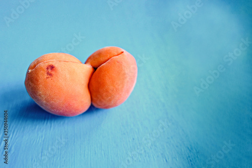 An ugly organic fruit-an oddly shaped yellow apricot on a blue background. Buying imperfect products is a way to deal with food waste. Copy space photo