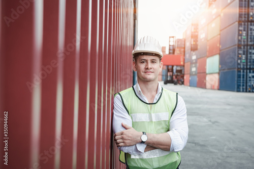 Bild auf Leinwand Portrait, Confident Transport Engineer Man in Safety Equipment Standing in Container Ship Yard
