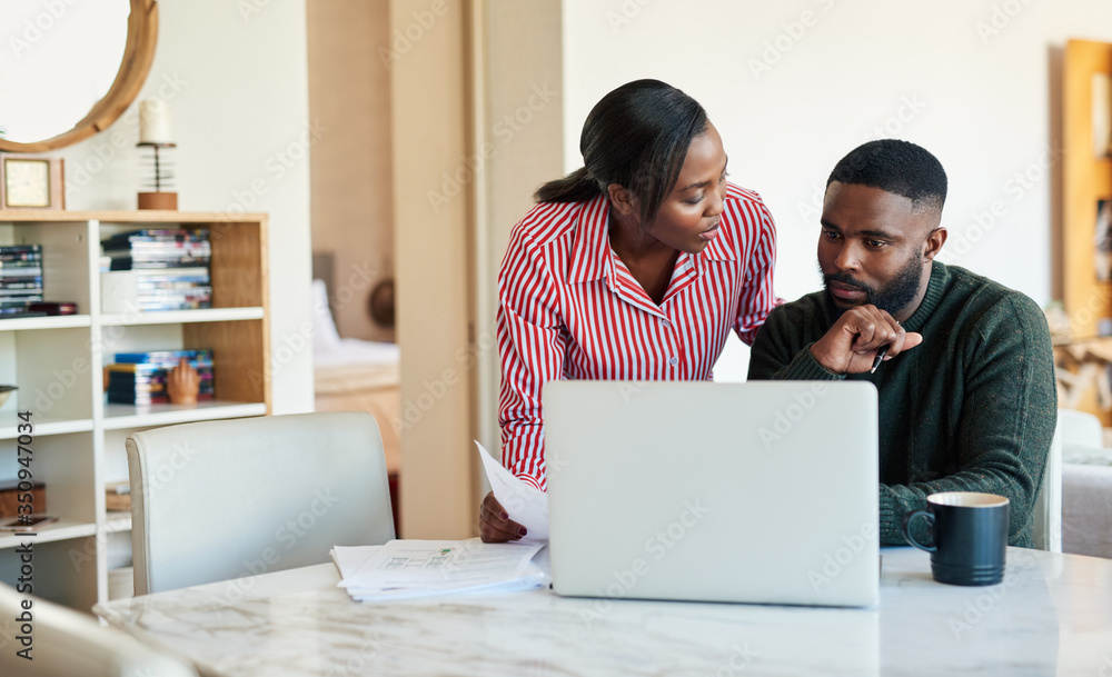 Young African American couple paying bills online with a laptop Young African American couple paying bills online with a laptop