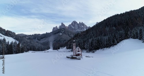Wide panning shot around snow covered Val Di Funes with Italian dolomites in the background