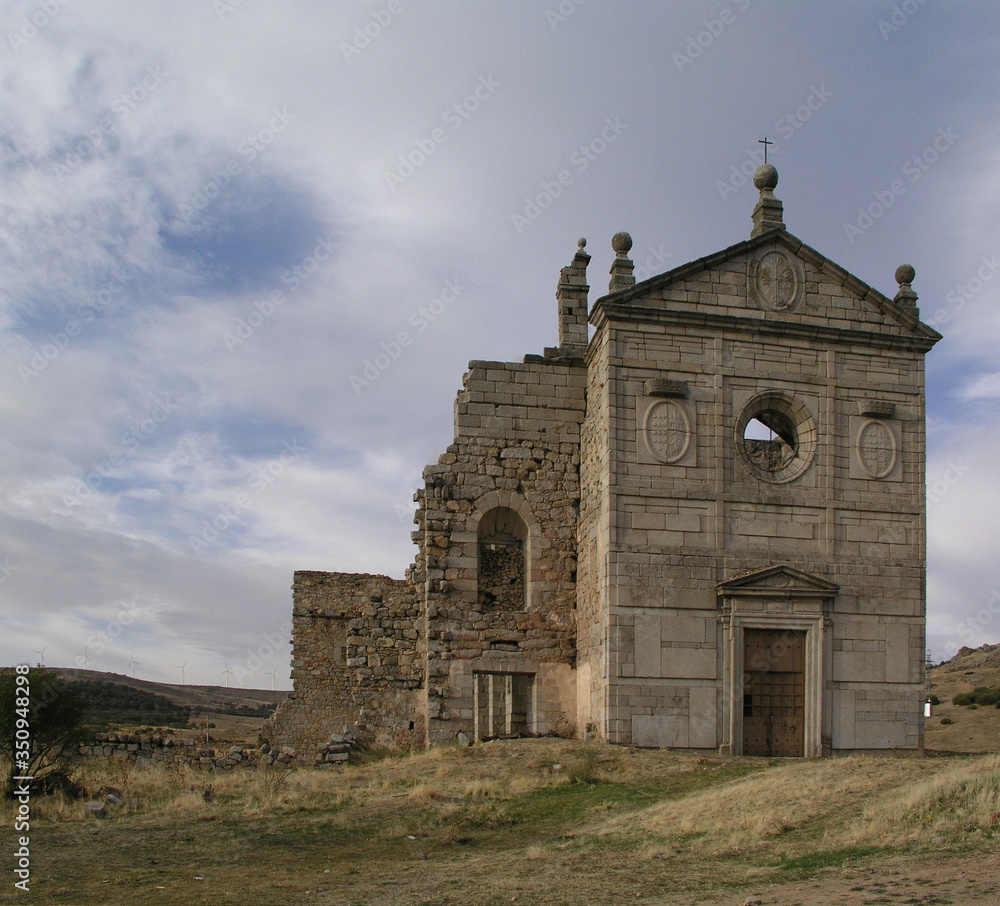 Old ruined Spanish church against a dramatic sky with storm clouds.
