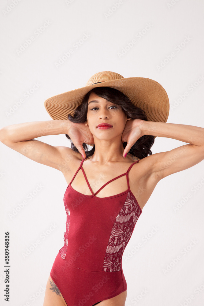 Beautiful woman in a red swimsuit and a straw hat looking thoughtful Beautiful woman in a red swimsuit and a straw hat looking thoughtful