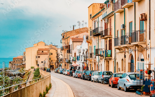 Cozy street with cars in Cefalu town Sicily reflex