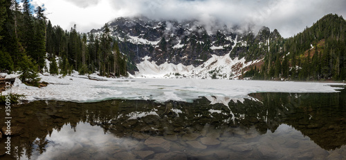 A snowbound lake shows reflections of snow covered mountains