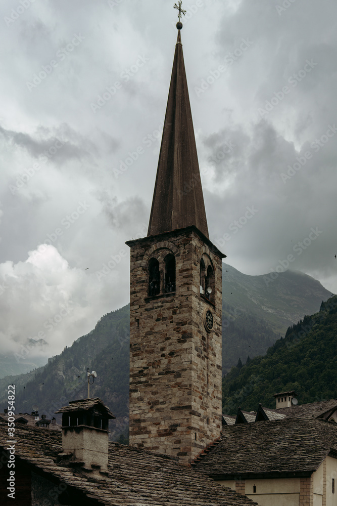 The bell tower of the old church among the alpine peaks