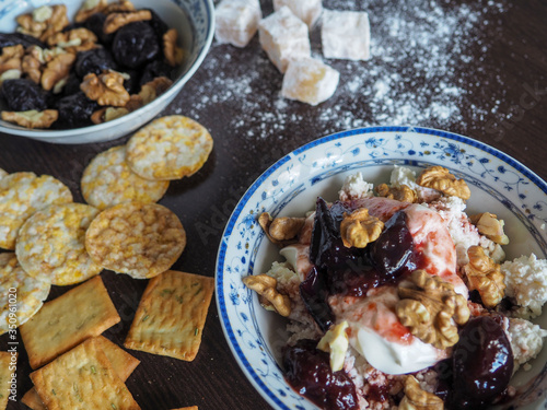 a plate of cottage cheese, nuts and jam and cereal on a dark surface for a healthy Breakfast