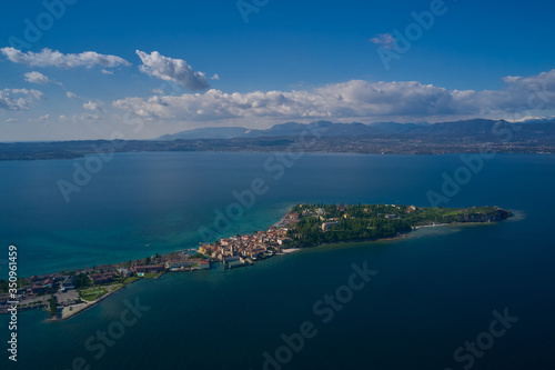 Fototapeta Naklejka Na Ścianę i Meble -  Sirmione town, Lake Garda, Italy. Aerial view of Sirmione high altitude. Side view of the island.