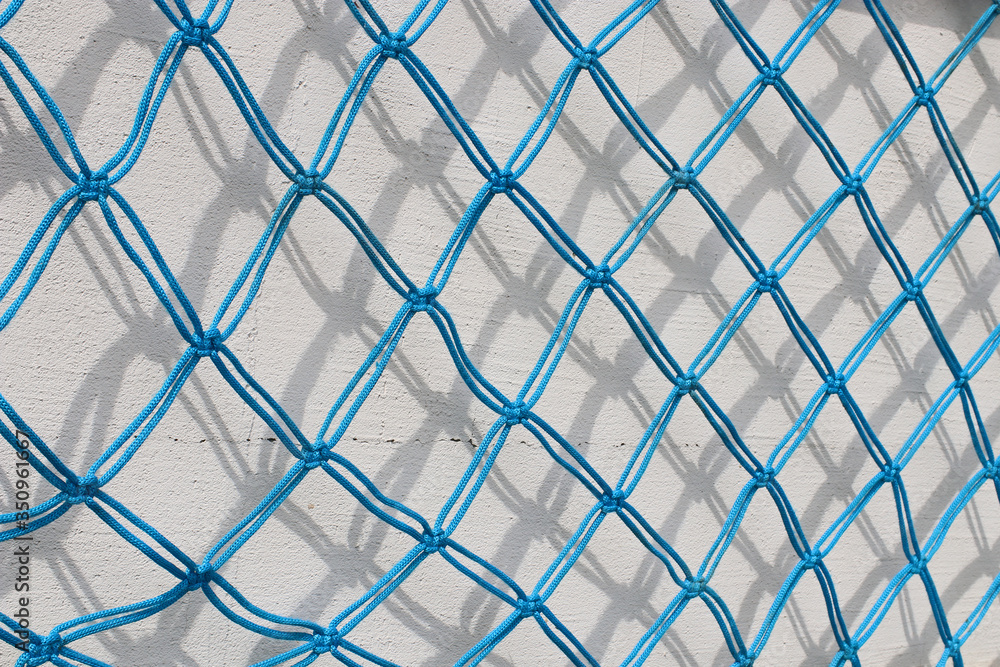 Fototapeta premium Fishnet against white wall. Handmade fishnet.