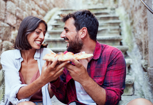 Sweet love couple eating pizza on street