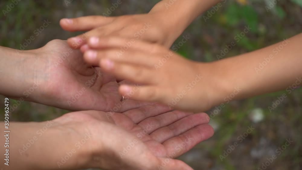 Close up video of anonymous little child hands touching hands of young mother with love. Happy family of mother and son or daughter having fun outside on summer day. Human hands at nature background. Close up video of anonymous little child hands touching hands of young mother with love. Happy family of mother and son or daughter having fun outside on summer day. Human hands at nature background.