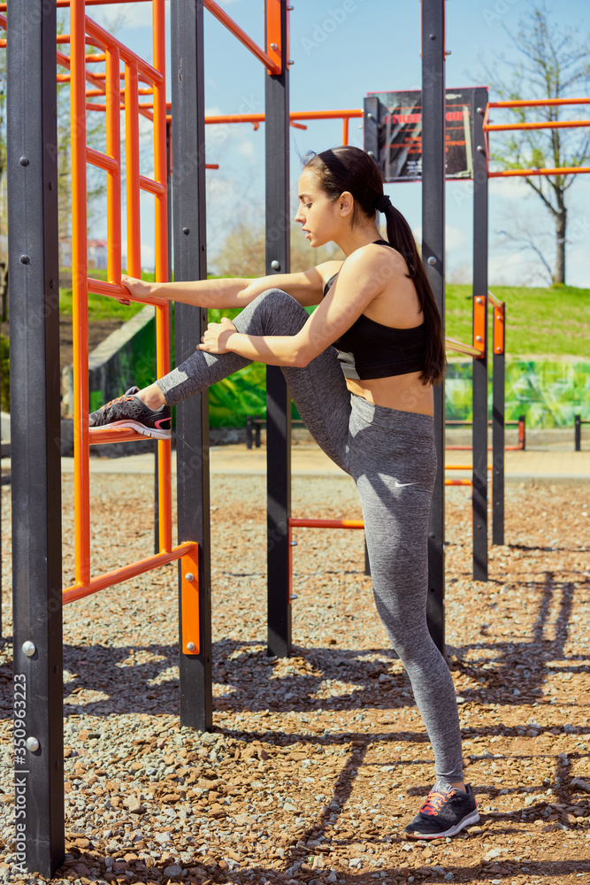 Fototapeta premium Beautiful fitness girl doing exercises in stylish sportswear outdoors. Crossfit. Outdoor training workout summer. Concept sport and healthy lifestyle. 