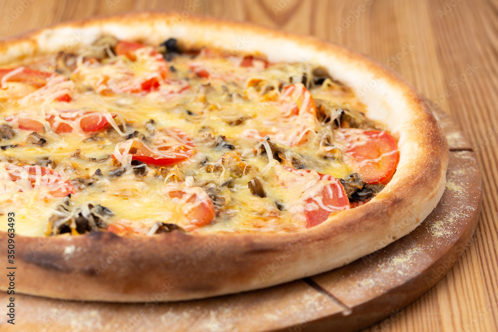 hearty italian pizza on a wooden board. .meat pizza with beef, fresh tomatoes, mushrooms and grated cheese