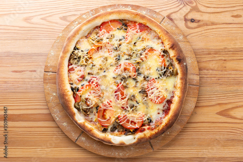hearty italian pizza on a wooden board. .meat pizza with beef, fresh tomatoes, mushrooms and grated cheese