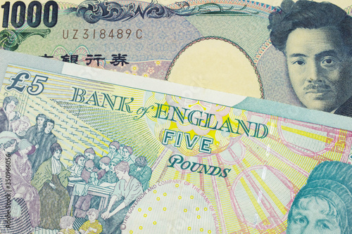 A macro image of a Japanese thousand yen note paired up with a colorful, five pound bank note from the United Kingdom.  Shot close up in macro.