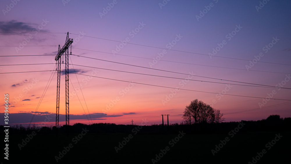 Silhouette of high voltage electric tower at beautiful sunset with dramatic clouds