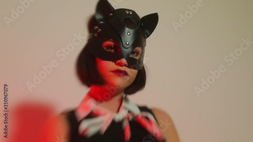 Dominant girl in cat mask posing at a party. Smooth focus movement. Dominatrix concept.