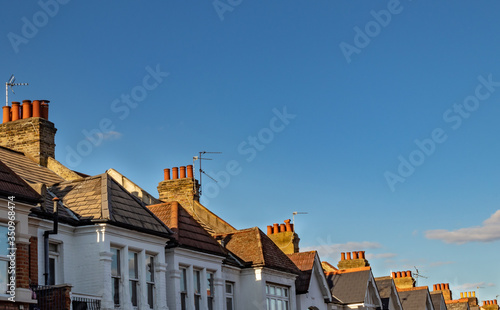 Fotografie Row of chimneys on rooftops with blue sky background