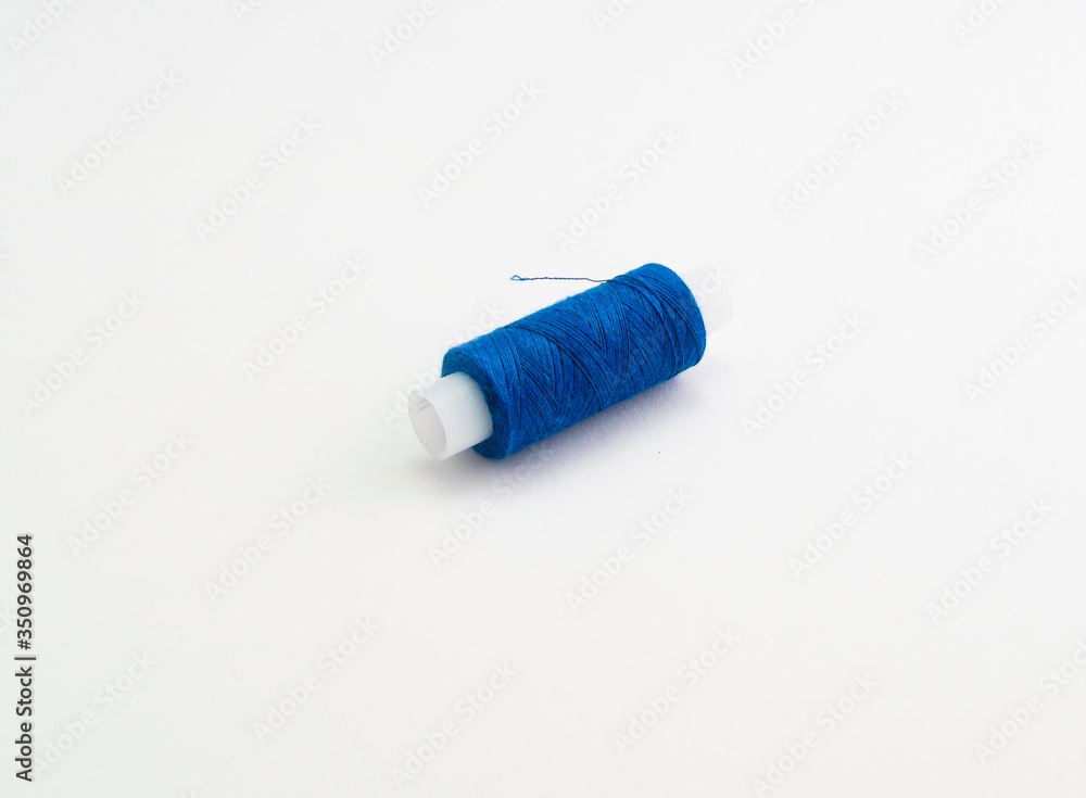 a spool of blue sewing thread on a white background a spool of blue sewing thread on a white background