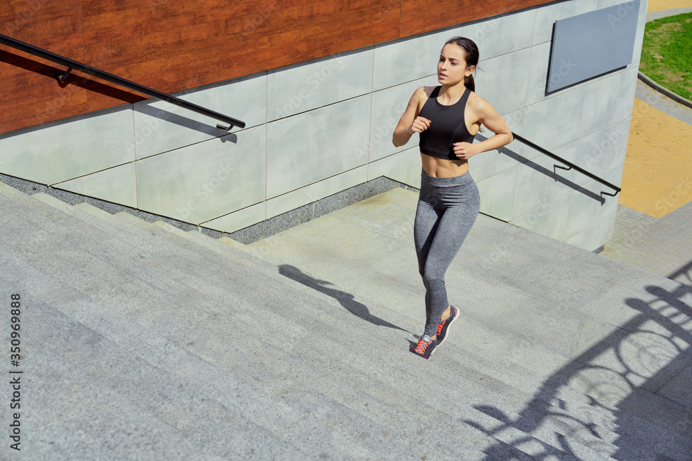 sportive young brunette woman walking on stairs. Beautiful fitness girl in stylish sportswear outdoors. sport and healthy lifestyle concept.