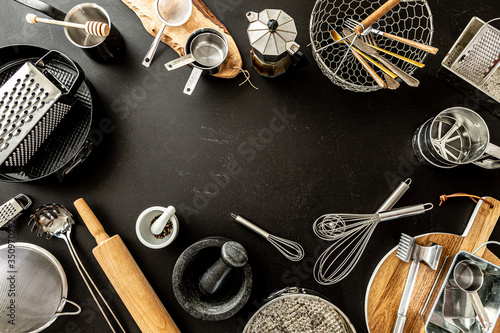 Kitchen utensils (cooking tools) on black background, free copy space