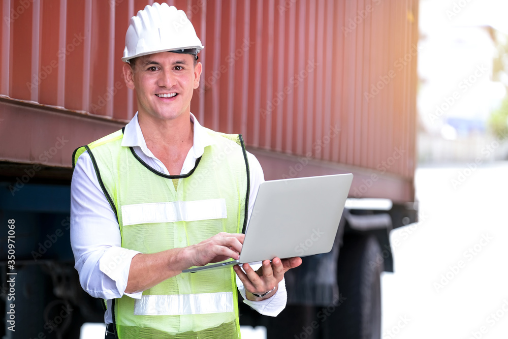 Engineer worker or technical standing in the container yard shipping area and used a laptop or computer to control loading containers into the truck. Industrial and import-export concept Engineer worker or technical standing in the container yard shipping area and used a laptop or computer to control loading containers into the truck. Industrial and import-export concept