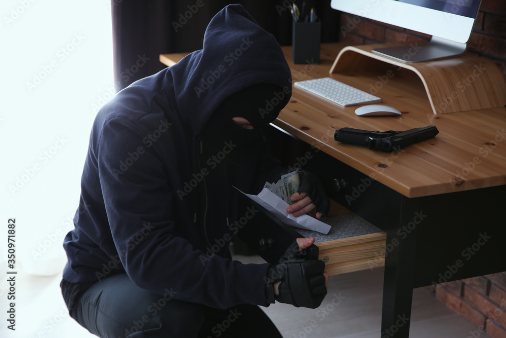 Dangerous masked criminal stealing money from house