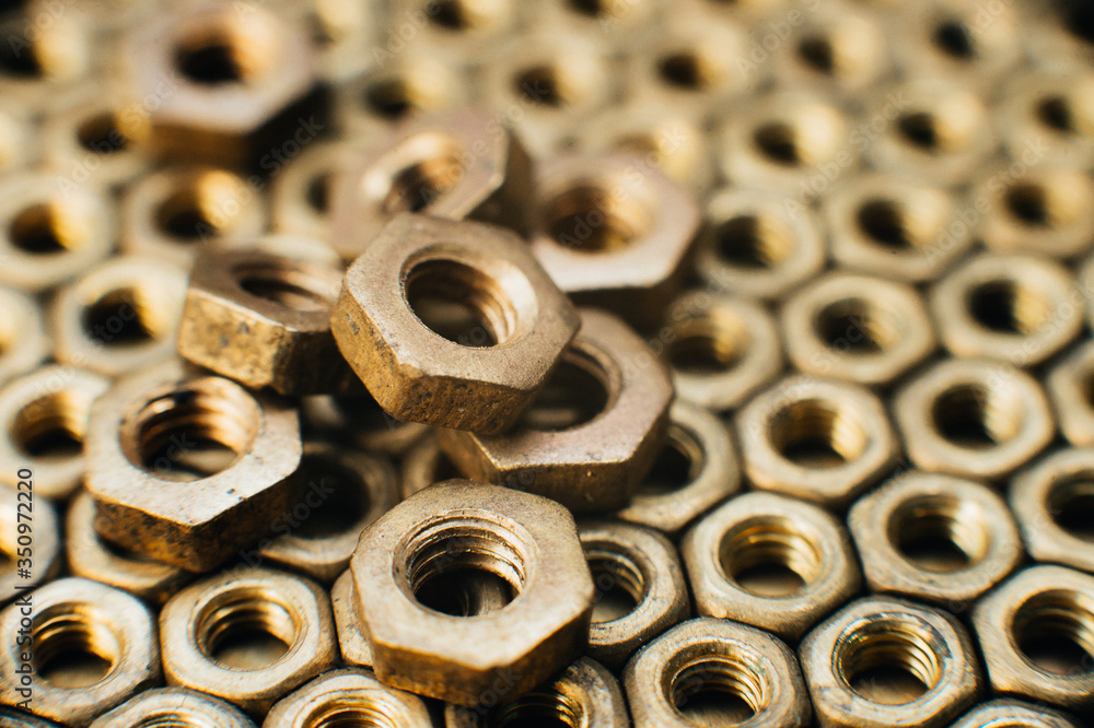 Close-up, macro. Old soviet brass nuts. Texture, background of brass nuts laid out in the form of honeycombs. Nuts of gold color. Dirty nuts in oil. Brass scrap metal Close-up, macro. Old soviet brass nuts. Texture, background of brass nuts laid out in the form of honeycombs. Nuts of gold color. Dirty nuts in oil. Brass scrap metal
