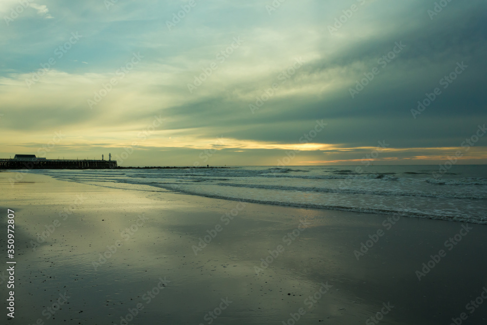 Beautiful sunset on the North Sea with pier and lighthouse in the background