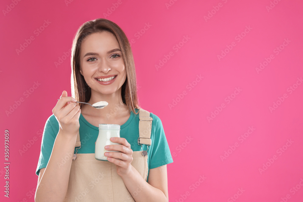Young attractive woman with tasty yogurt on pink background. Space for text Young attractive woman with tasty yogurt on pink background. Space for text