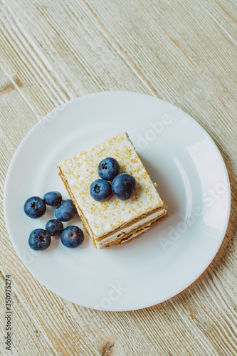 Honey cake with blueberries in a white saucer on the table